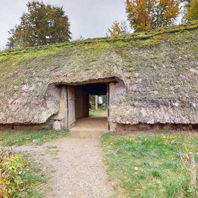 Eingang des Langhauses II mit grasbewachsenem Dach im Freilichtmuseum
